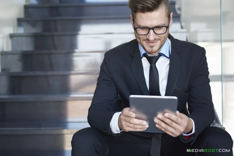 Мужчина сидит на лестнице с планшетом и ведет бухгалтерию онлайн